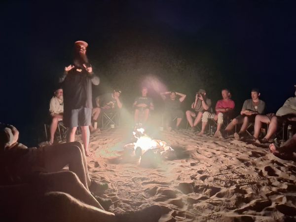 A speaker and hikers gathered around a campfire