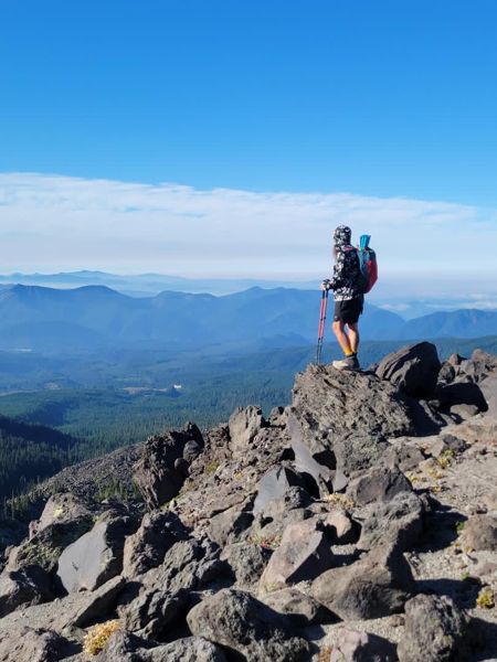 A hiker standing on a rocky mountain summit