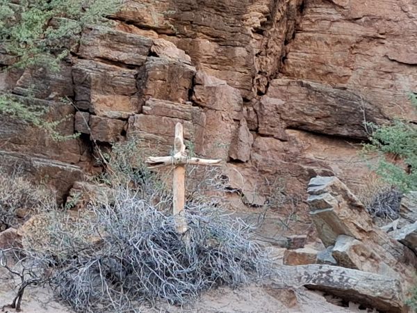 A wooden cross beside a rocky trail