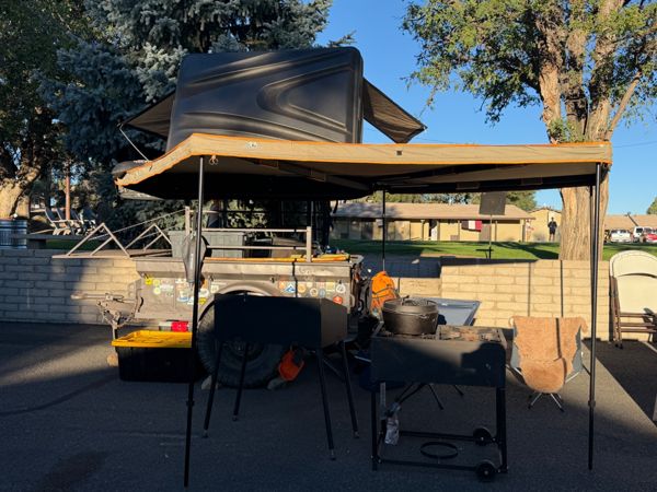 A vehicle with a rooftop tent and outdoor cooking setup