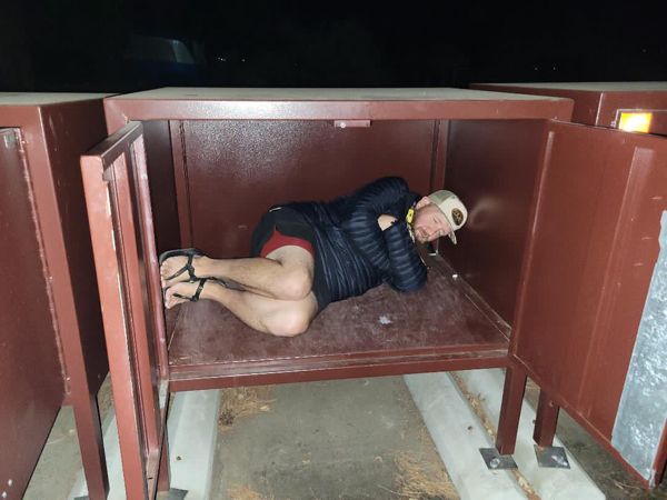 A hiker resting inside a campsite storage box